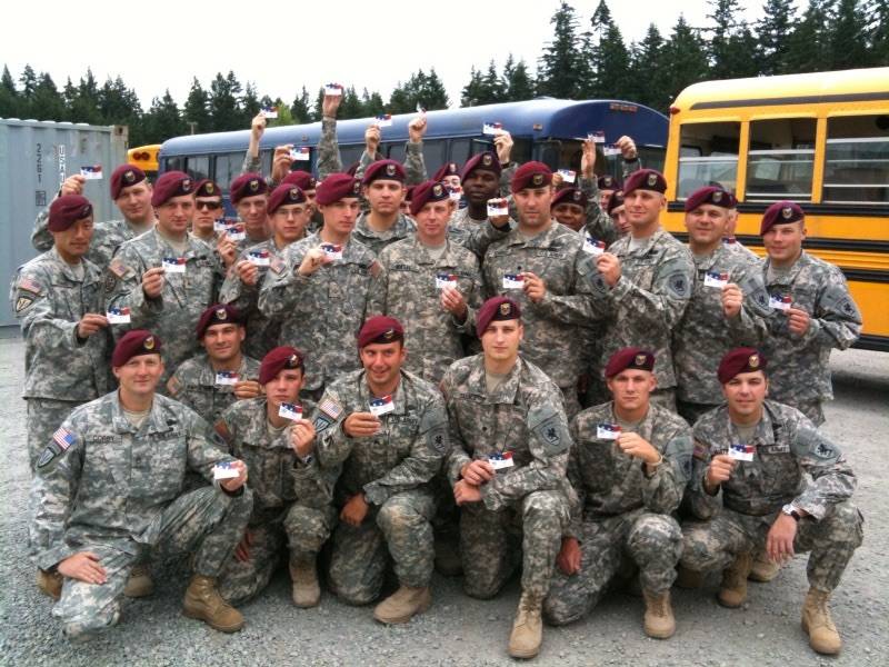 Group of uniformed soldiers proudly displaying Cell Phones for Soldiers calling cards.